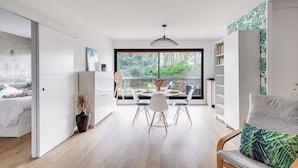 Ein modernes Interieur mit Essbereich, einem Bett und Blick durch ein großes Fenster.