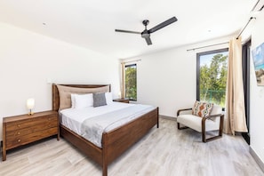 A bedroom with a bed, nightstand, chair, ceiling fan, and large windows. - Bougain Villa TCI New Luxury Villa Near Grace Bay (Grace Bay)
