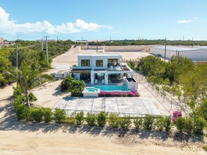 A modern two-story house with a swimming pool, surrounded by greenery and a clear sky. - Bougain Villa TCI New Luxury Villa Near Grace Bay (Grace Bay)