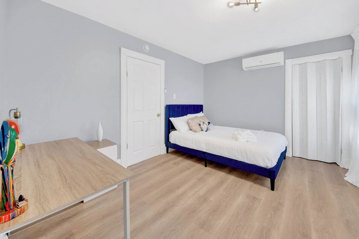 A bedroom with a bed, a desk, and a door.