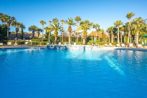 A pool with clear blue water, surrounded by palm trees and lounge chairs. - Dog friendly ~ FREE golf cart & bikes ~End of summer 15% off ~ Club & pool (Destin)