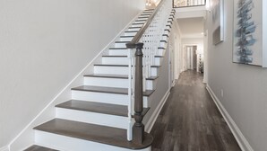 Eine Treppe mit weißen Stufen und dunklen Holzhandläufen, die zu einer zweiten Etage führt.