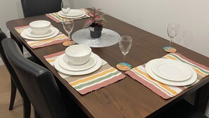 Une table à manger dressée avec des assiettes, des bols et une plante en pot.