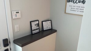 Un espace d’accueil avec une pancarte de bienvenue, un thermostat numérique et deux tableaux encadrés posés sur un comptoir.