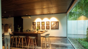 Uma cozinha moderna com teto de madeira, área de bar com banquetas e obras de arte emolduradas na parede.