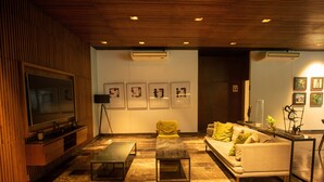 Uma sala de estar moderna com um sofá, duas mesas de centro, uma televisão e obras de arte nas paredes.