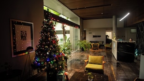 Um lobby moderno com árvore de Natal, área de estar e balcão de recepção.