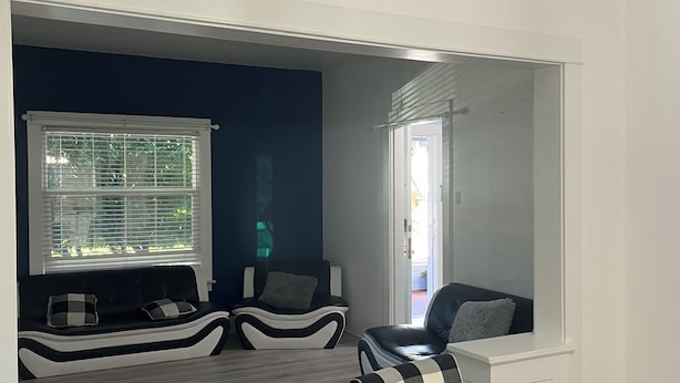Uma sala de estar moderna com um sofá, uma mesa de jantar e uma vista por uma porta.