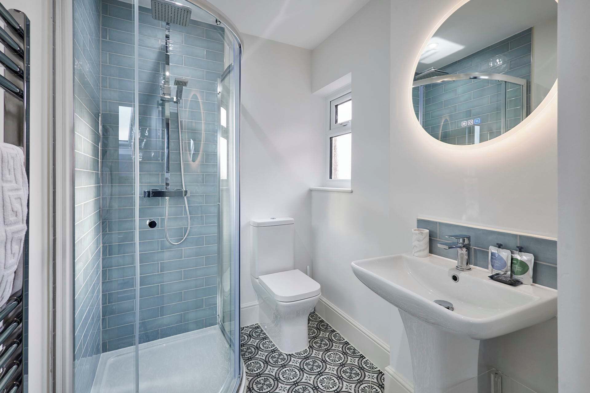 A modern bathroom with a glass-enclosed shower, a toilet, and a sink with a mirror above it.