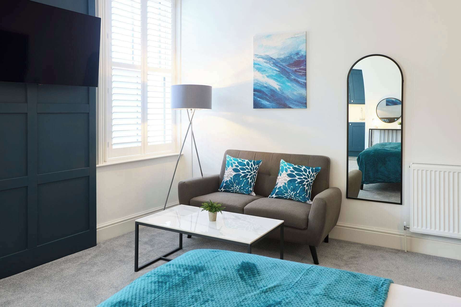 A modern living room with a sofa, coffee table, and a large mirror.