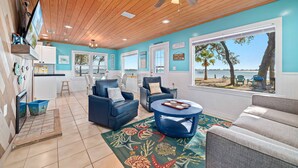A spacious living area with a view of the beach, wooden ceiling, and modern furniture. - Bama Breeze | Little Lagoon w/ Fishing Dock | Dog Friendly | My Beach Getaways (Gulf Shores)