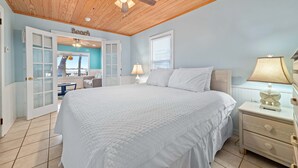 A bedroom with a large bed, a ceiling fan, a nightstand with a lamp, and a door labeled "Beach". - Bama Breeze | Little Lagoon w/ Fishing Dock | Dog Friendly | My Beach Getaways (Gulf Shores)