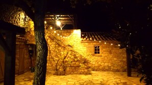 Un edificio de piedra con techo de tejas, una ventana pequeña y luces colgantes.