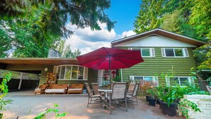 A patio with a table and chairs, an umbrella, and potted plants. - Cozy 3BR Villa Garden View Beach (Surrey)