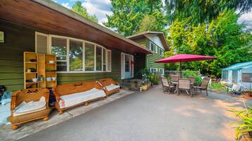 A house with a covered porch, wicker furniture, and a dining area with a table and chairs.