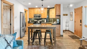Una cocina moderna con armarios de madera, electrodomésticos de acero inoxidable y una isla central con taburetes.