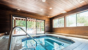 Una piscina con techo de madera y grandes ventanales.