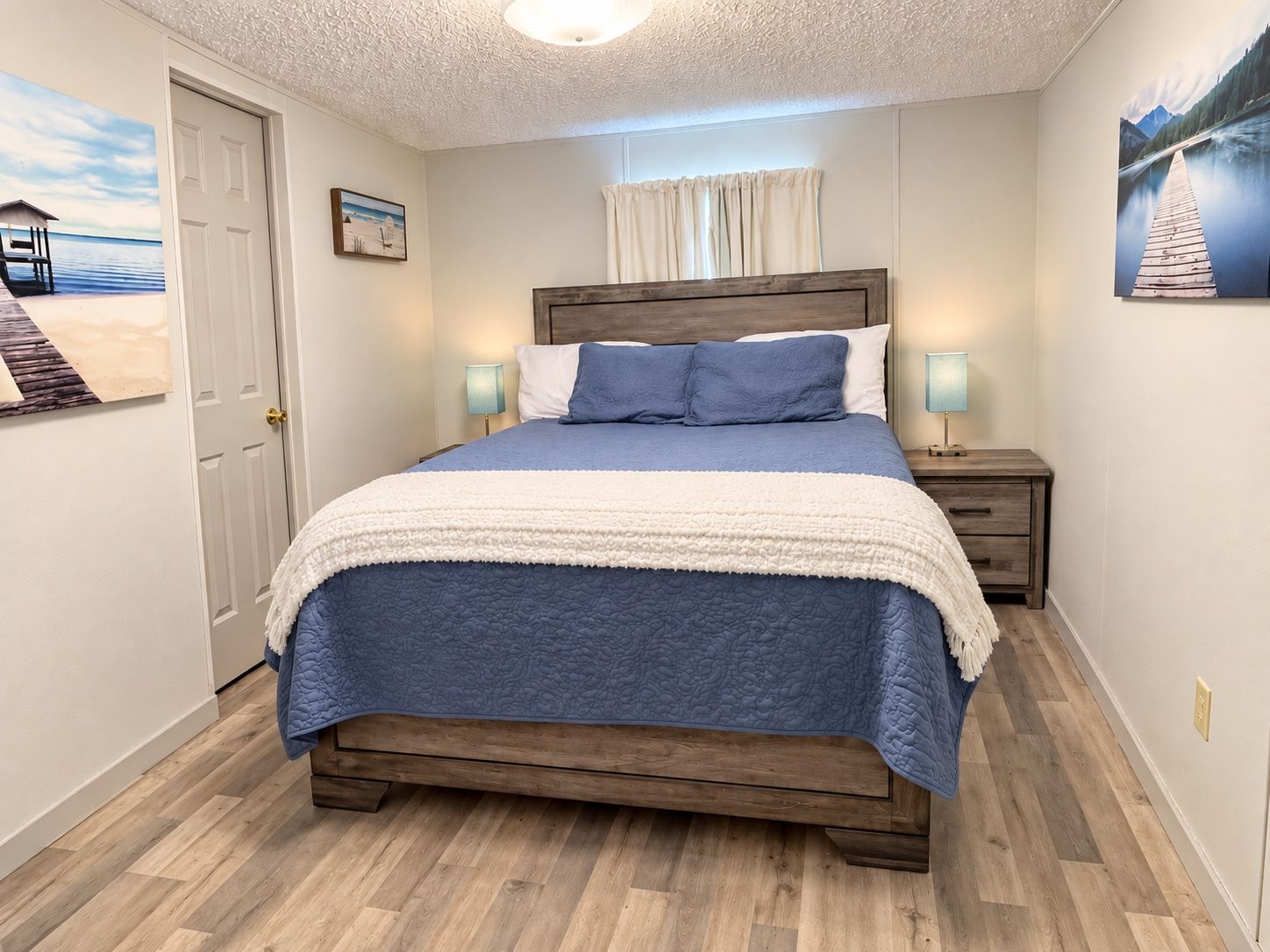 A bedroom with a wooden bed, a white door, and a nightstand with a lamp.