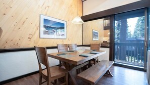 Ein Essbereich mit Holzboden, einem großen Tisch, Bänken und gerahmten Bildern an der Wand.