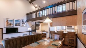 Un interior moderno con comedor, cocina y una escalera que lleva a un nivel superior.