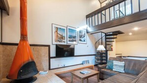 Una sala de estar moderna con chimenea, un sofá, una mesa de centro y un televisor montado en la pared.