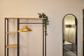 A room with a wooden shelving unit, a hanging garment, and a potted plant. - Host Stay The Langley Hotel Apartment 12 (Whitby)