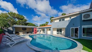 Une maison moderne dotée d’une piscine, d’un patio couvert et d’une pelouse bien entretenue.