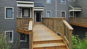 Un immeuble résidentiel à plusieurs étages doté d’une terrasse en bois et d’une passerelle couverte.