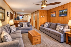 Ein gemütliches Wohnzimmer mit zwei grauen Sofas, einem Holztisch und einem Deckenventilator.