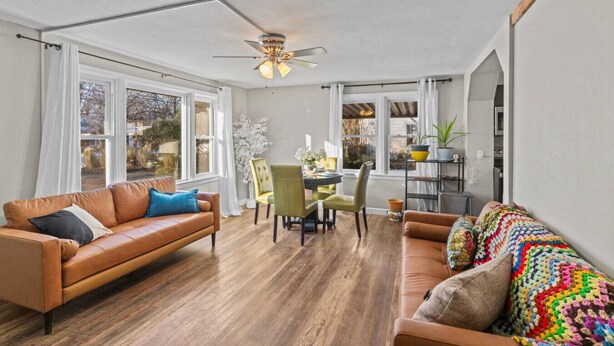 A spacious living room with a brown leather sofa, a colorful knitted throw, and a dining area with a table and chairs. - Safe, Quiet home with huge Fenced yard and parking (Maryland Heights)