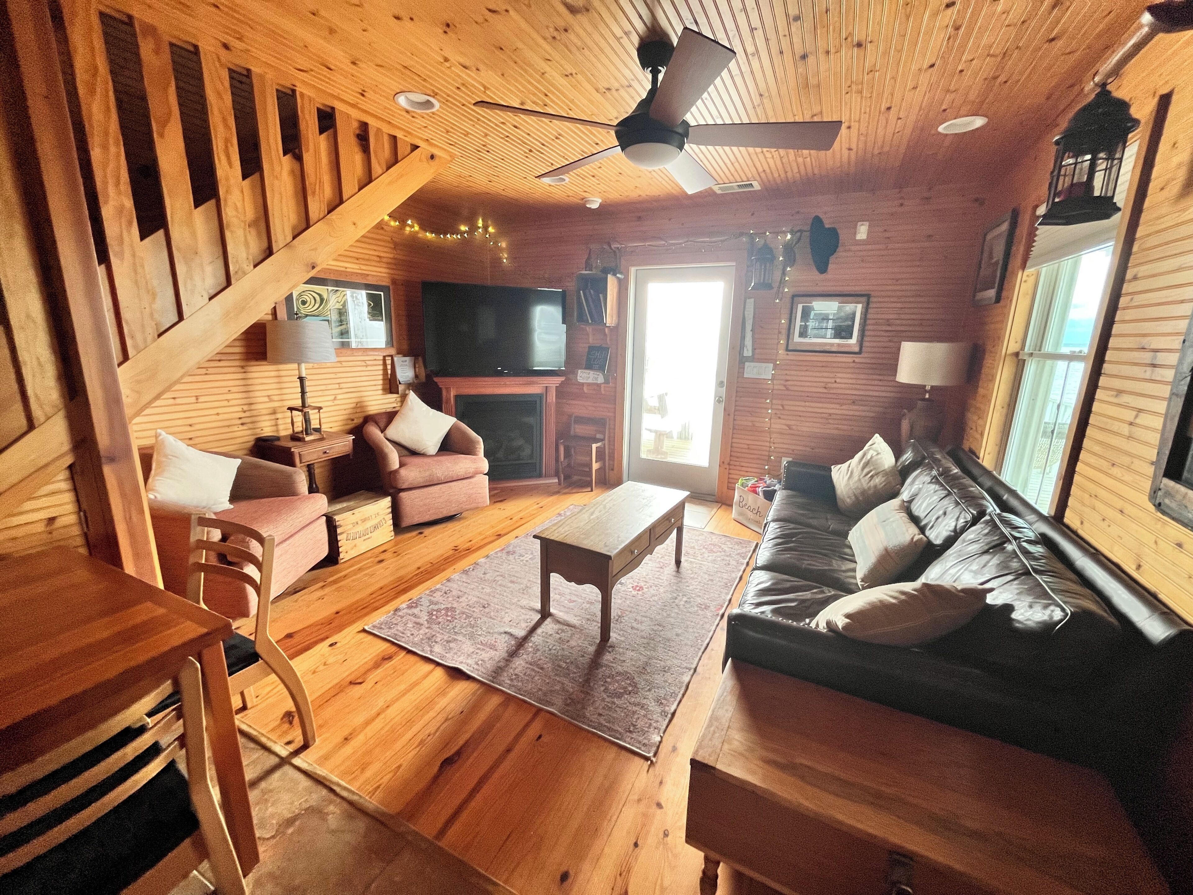 Un intérieur en bois comprenant un canapé, des fauteuils, une table basse, un téléviseur et une cheminée.