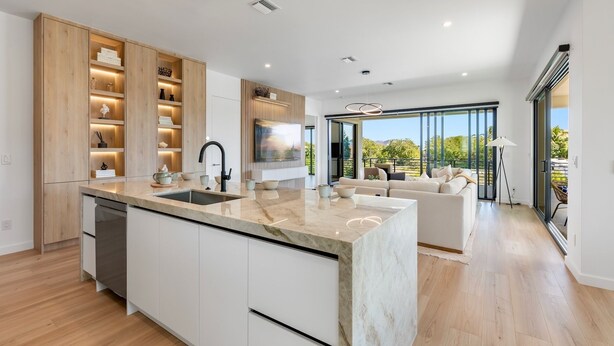 A modern kitchen with a marble countertop, integrated dishwasher, and wooden cabinetry. - Upscale Canal-Front Escape w/ Private Pool, Dock & Water Views (Cudjoe Key)