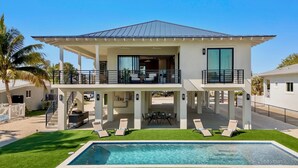 A two-story house with a pool, outdoor seating, and a covered patio. - Upscale Canal-Front Escape w/ Private Pool, Dock & Water Views (Cudjoe Key)