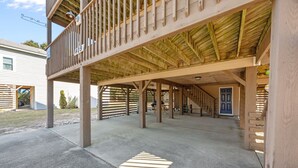Un espace extérieur abrité, doté d’un sol en béton, de poutres en bois et d’une porte bleue à l’arrière-plan.