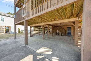 Ein überdachter Außenbereich mit Betonboden, Holzbalken und einer blauen Tür im Hintergrund.