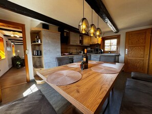 Una cocina moderna con una isla de madera, luces colgantes y un comedor con una mesa grande y un banco.