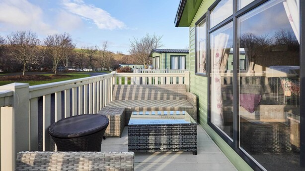 A balcony with wicker furniture, a glass door, and a view of a park. - Host and Stay 421 Wooler Park (Wooler)