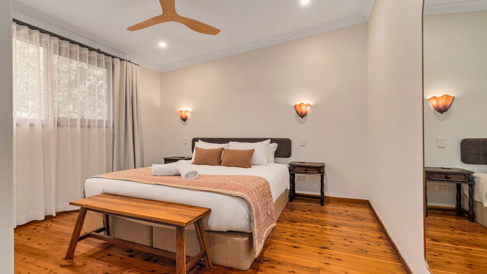 A neatly arranged bedroom with a wooden bed, a bedside table, and a bench.