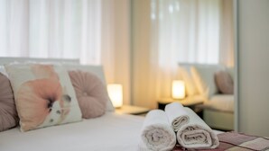 A neatly made bed with rolled towels, a floral pillow, and a bedside table with a lamp. - Your Calm Corner in Lane Cove North (Lane Cove North)