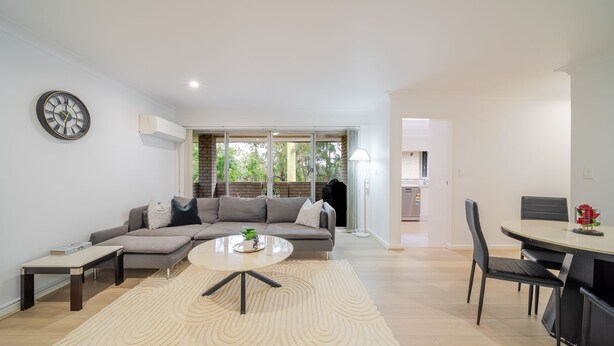 A modern living room with a sectional sofa, a coffee table, and a dining area with a table and chairs. - Your Calm Corner in Lane Cove North (Lane Cove North)