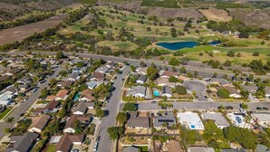 An aerial view of a residential area with houses, roads, and a lake. - Quiet and Spacious 4BR Goleta Home with a Big Yard and Near Beaches & UCSB (Goleta)