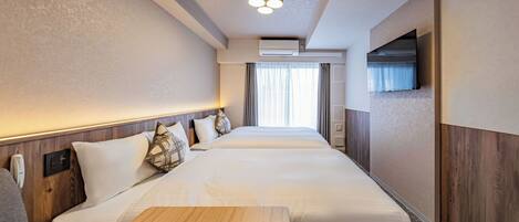 Habitación de hotel con una cama grande, cabecera de madera, televisor de pantalla plana en la pared y una ventana con cortinas.