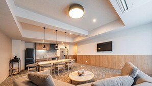 A modern living room with a sofa, coffee table, and dining area. - Apartment Hotel 11 Nambaminami 5 (Osaka)