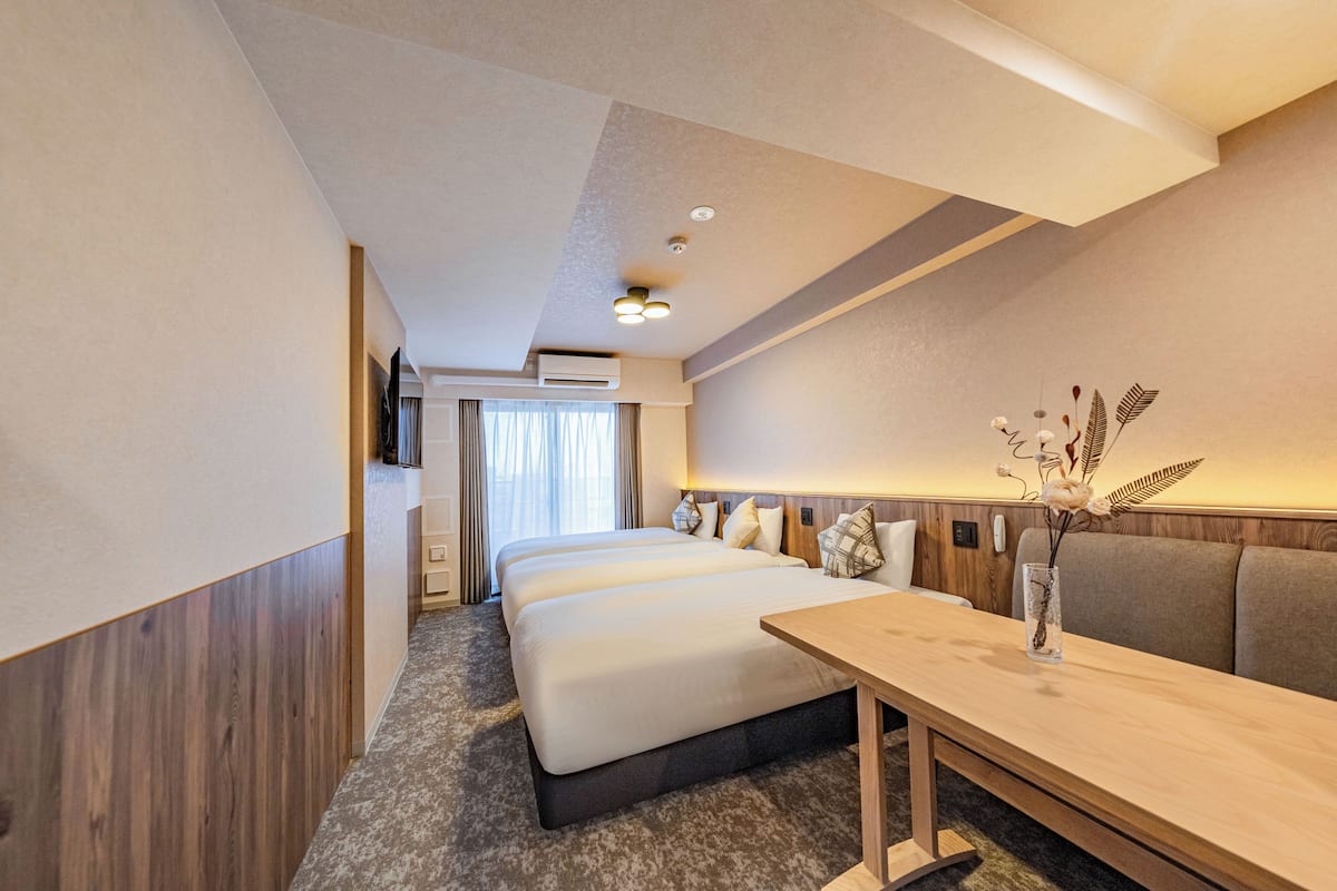 A hotel room with a large bed, a wooden desk, and a vase with flowers.