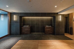 Un baño moderno con dos lavamanos, baldosas oscuras e iluminación empotrada.