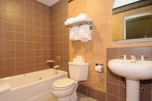 A bathroom with a bathtub, toilet, and sink. There are towels hanging on a rack above the toilet. - Shoshone Condominiums (Gallatin Gateway)