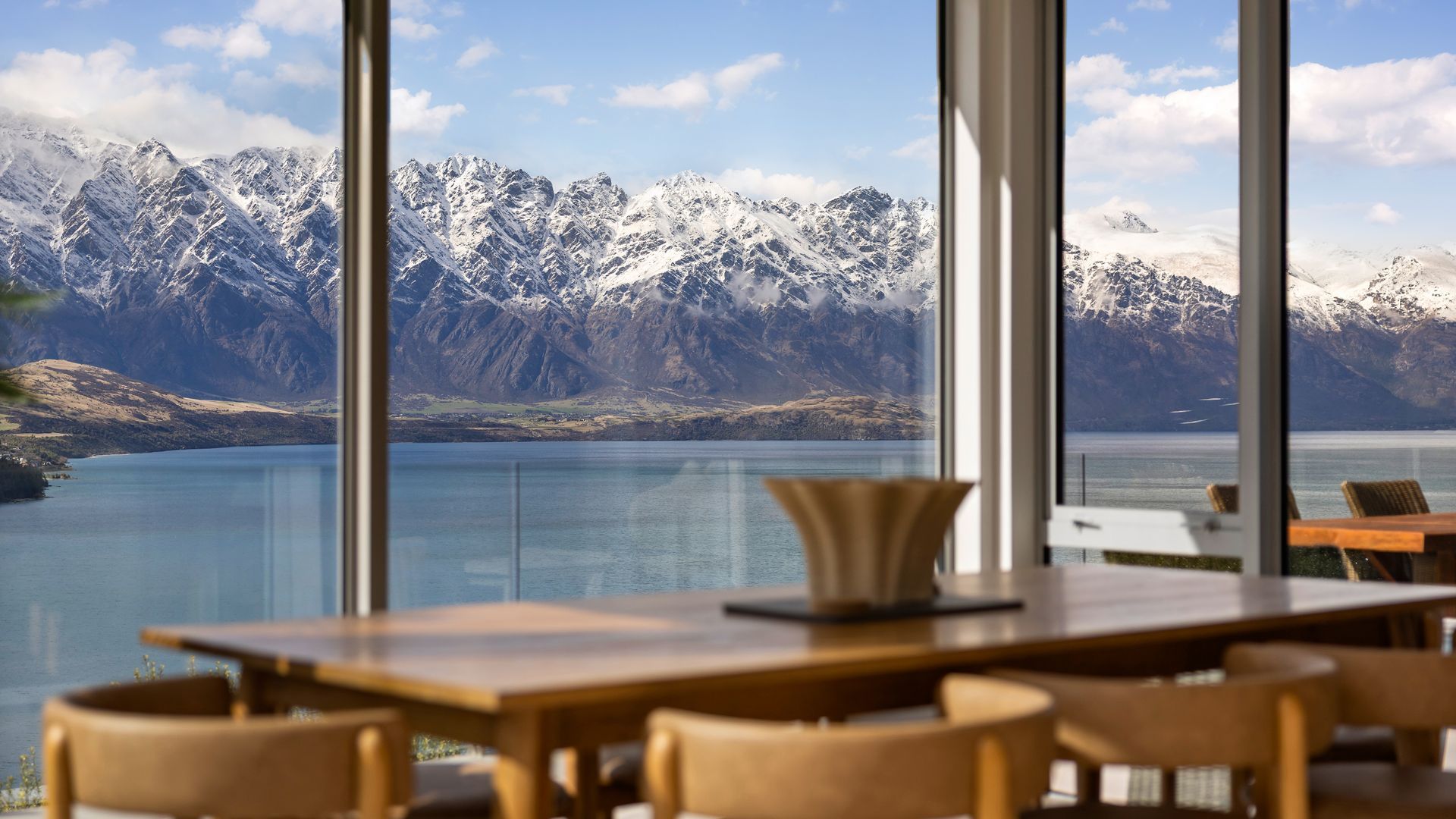 A dining area with a view of snow-capped mountains and a lake.