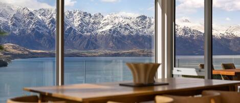 A dining area with a view of snow-capped mountains and a lake.