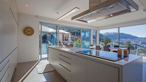 Una cucina moderna con una grande isola, una zona pranzo con vista e un'ampia finestra che si affaccia su un paesaggio montuoso.