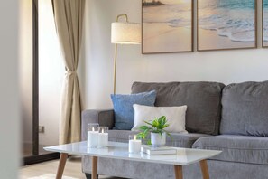 Ein modernes Wohnzimmer mit einem weißen Couchtisch, einem grauen Sofa und einer Stehlampe.